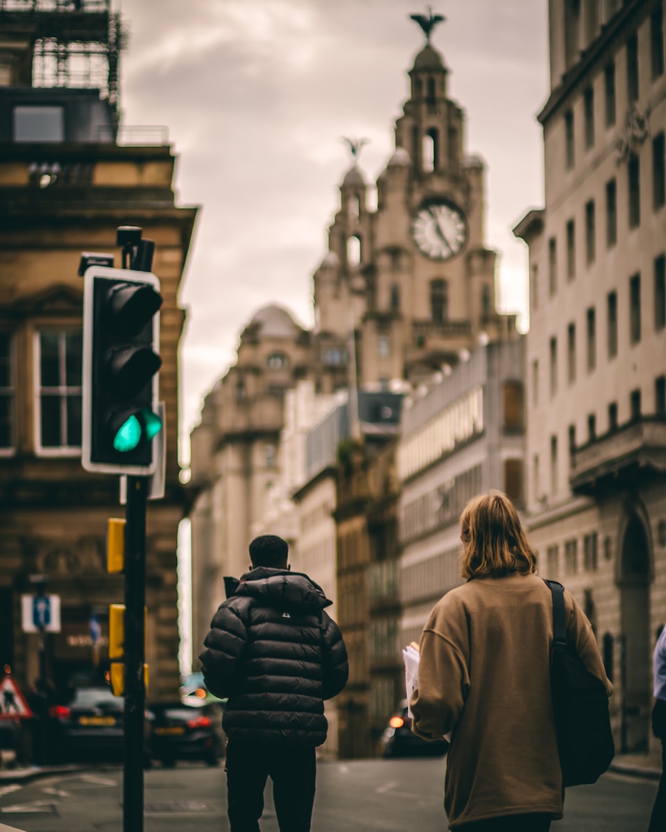 woman in brown coat standing near traffic light during daytime